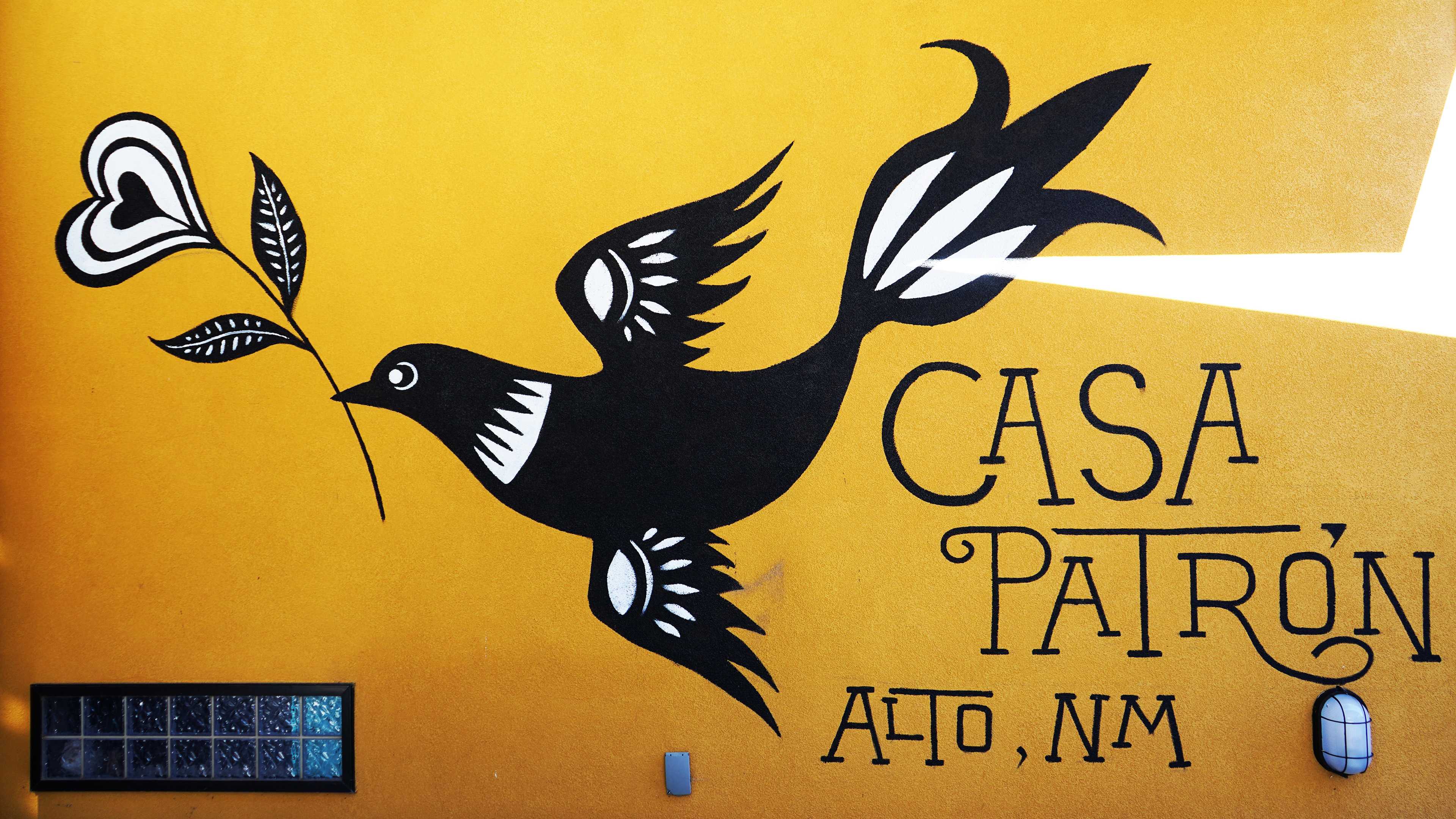 The Casa Patron mural, a black bird painted over a yellow background.